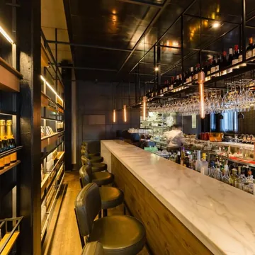 The long marble bar lined with leather stools and backlit champagne shelves